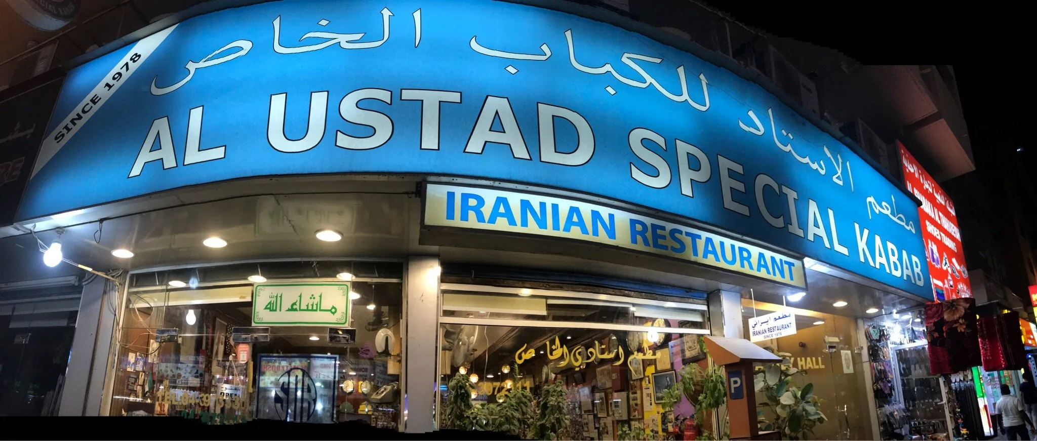 The blue-canopied storefront of Al Ustad Special Kabab, Al Mankhool Road, Bur Dubai, lit up at night
