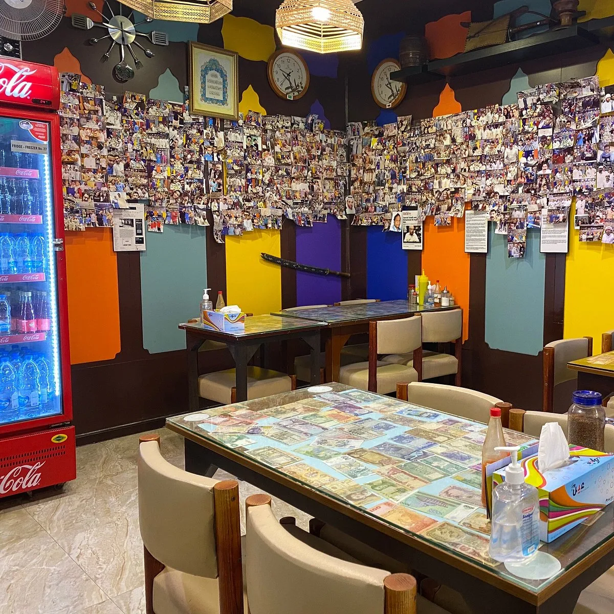 The Al Ustad dining room from the door — Coca-Cola fridge, photo wall, currency-glass tables