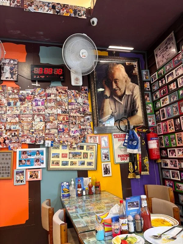 A framed portrait of Haji Mohammad Ali Ansari, the founder, hangs above the dining room — surrounded by the photo wall