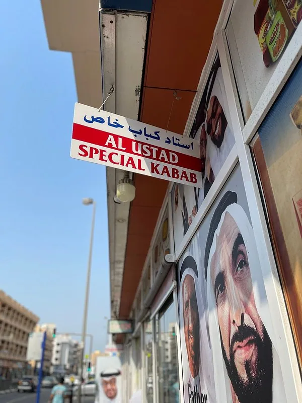 Close-up of the red-and-white hanging Al Ustad Special Kabab sign, with portraits of UAE leaders visible alongside