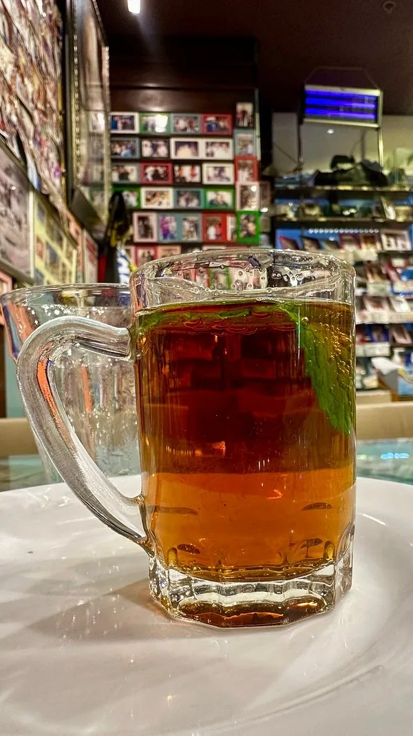 A glass mug of mint tea on a white plate
