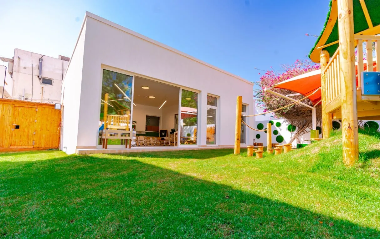 A bright, prepared Montessori classroom at the Palm Jumeirah campus — round wooden tables, child-height materials, and natural light.