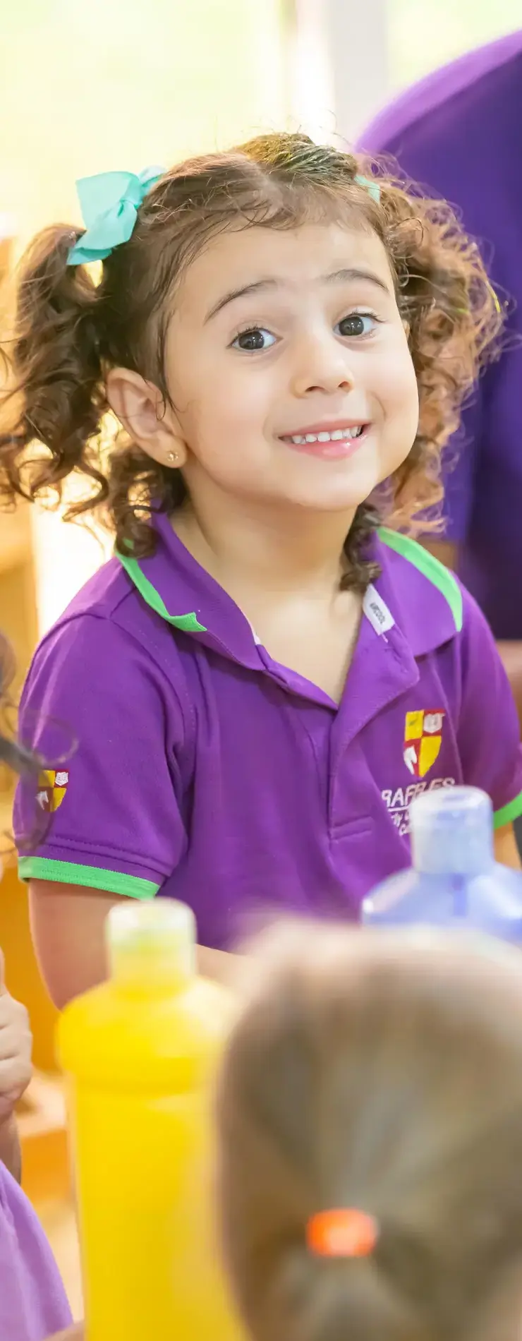 A child in the Raffles ECC uniform, smiling during messy play.