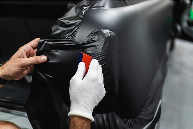Black vinyl wrap being squeegeed into place