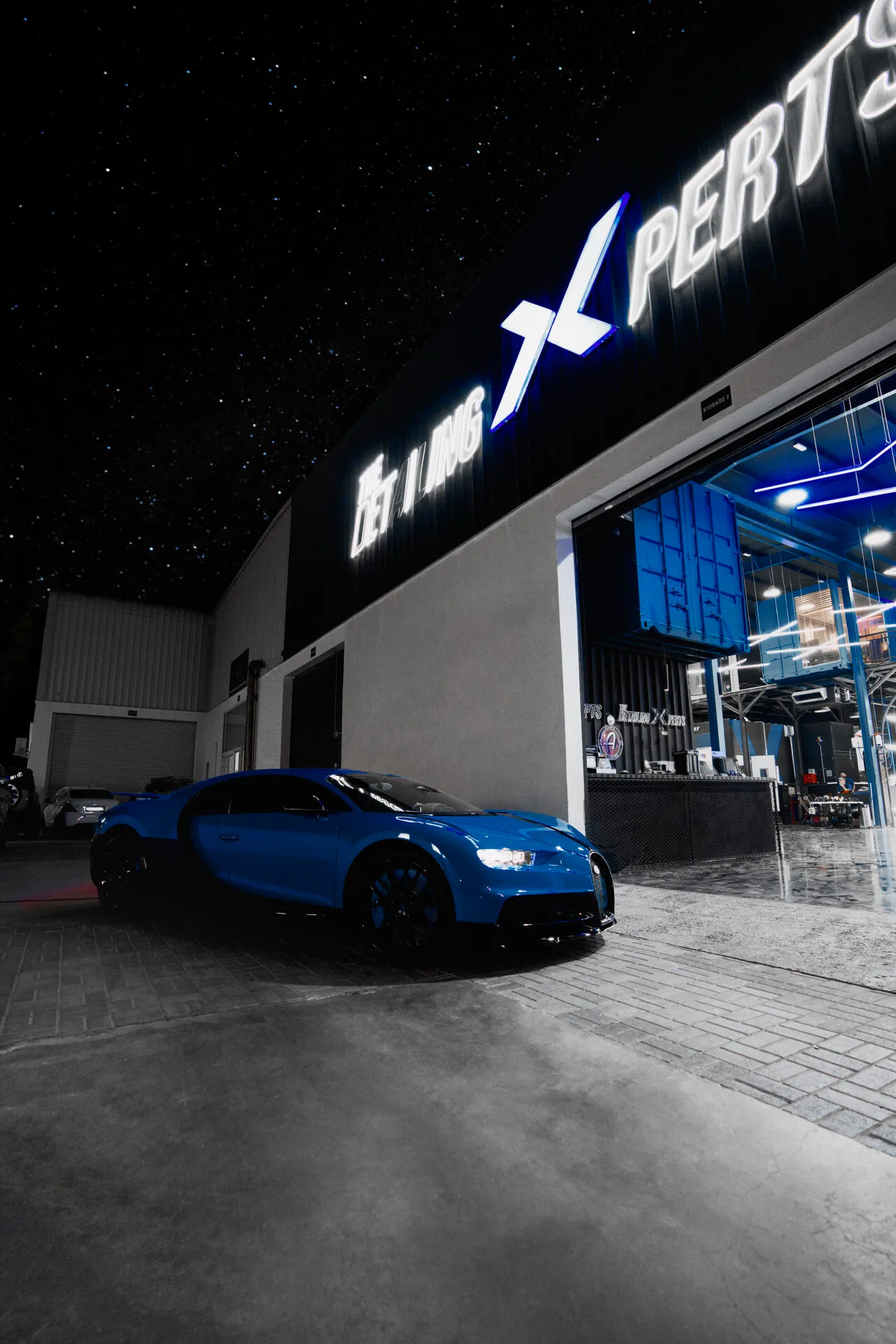 A Bugatti outside The Detailing Experts' lit Dubai workshop at night