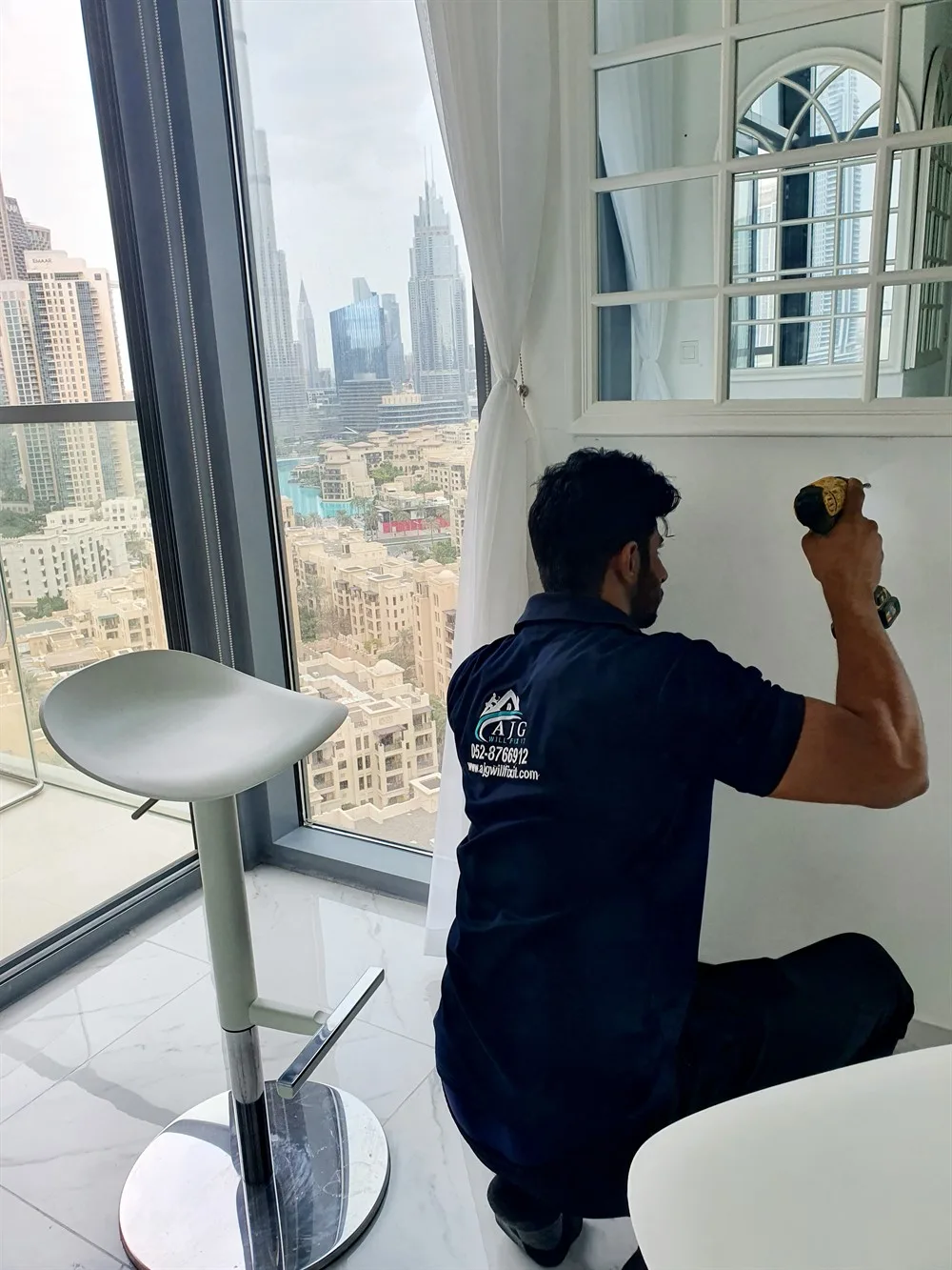 AJG technician in branded uniform carrying out a repair in a Downtown Dubai apartment overlooking the skyline