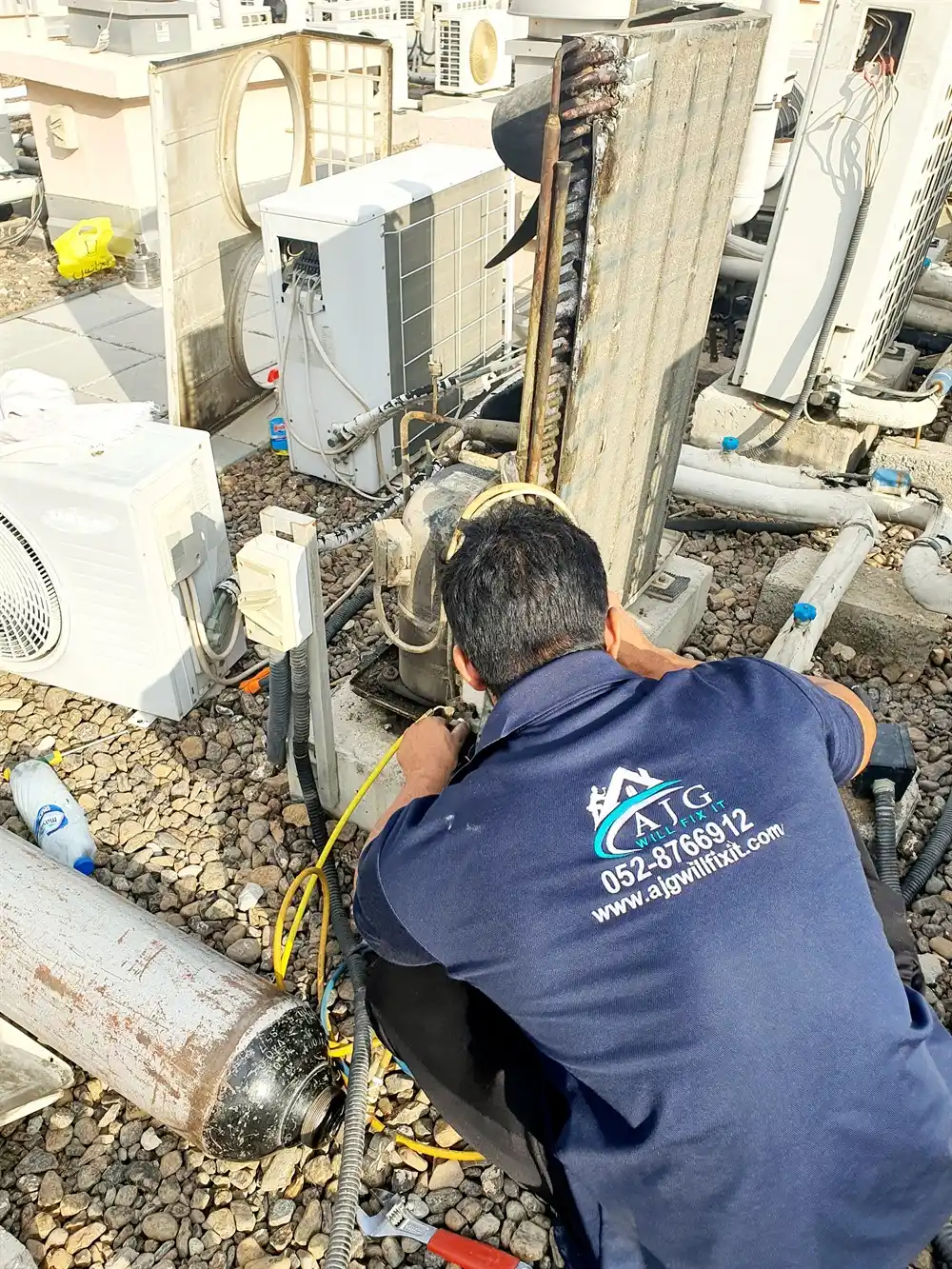 AJG technician servicing a rooftop AC condenser in Dubai