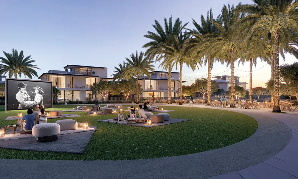Low-rise homes beside a palm-lined community lawn at dusk