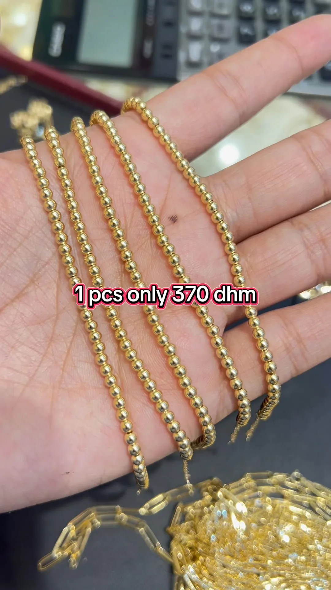 Gold beaded chains held in hand