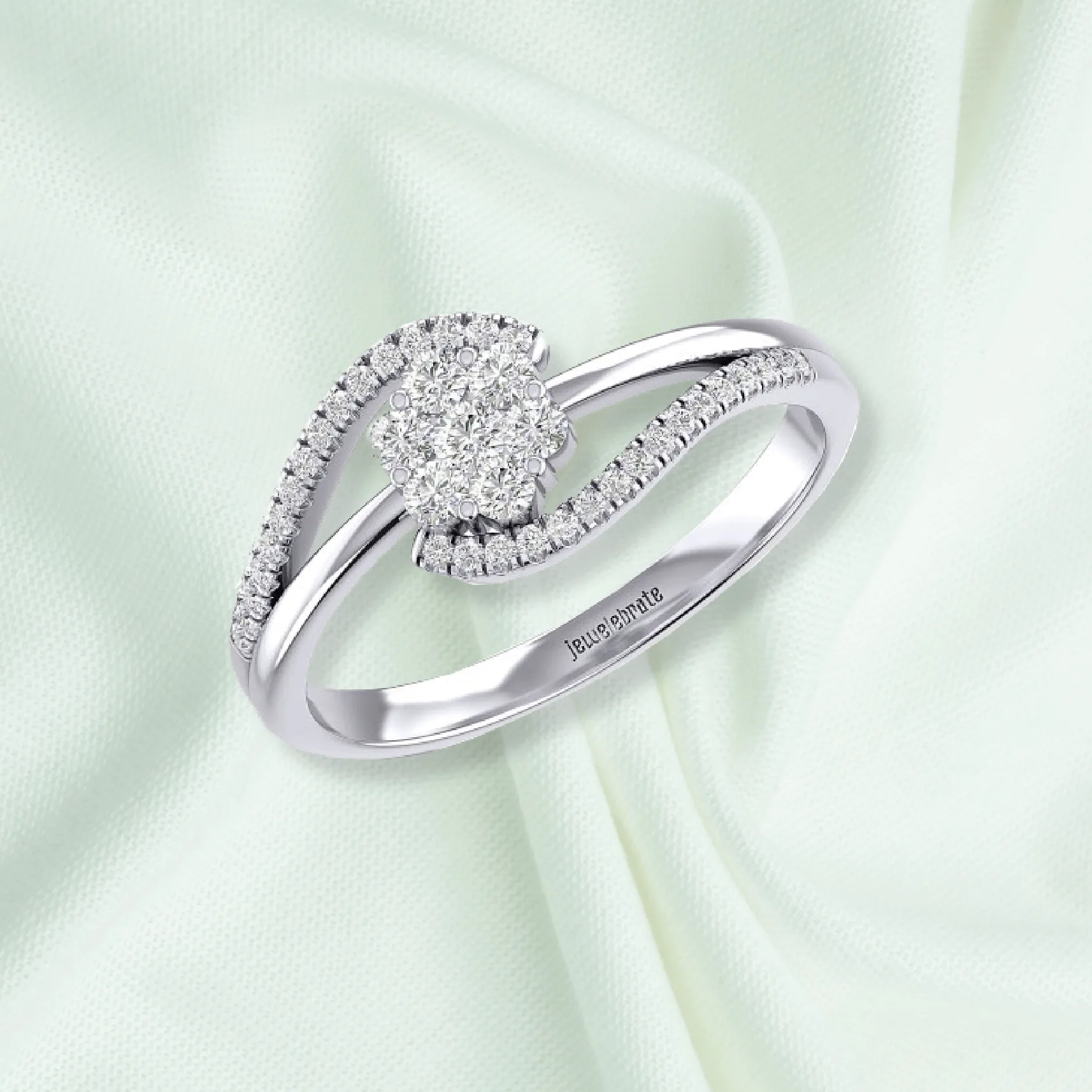 A white-gold diamond bypass ring resting on soft celadon silk.