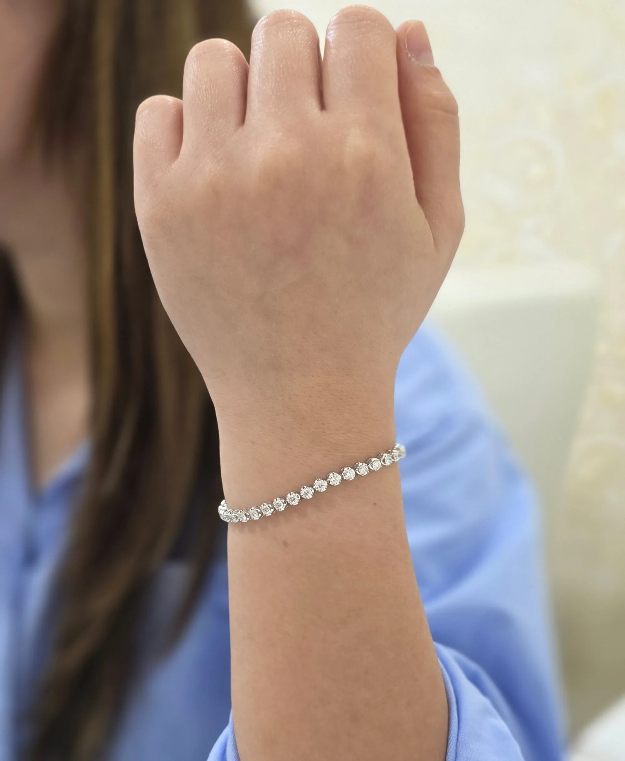 A diamond tennis bracelet worn on the wrist.