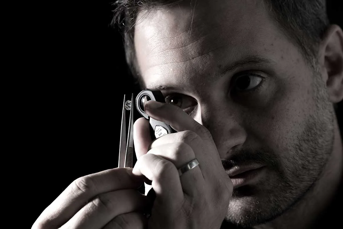 A Fergus James gemologist inspecting a loose diamond through a jeweller's loupe