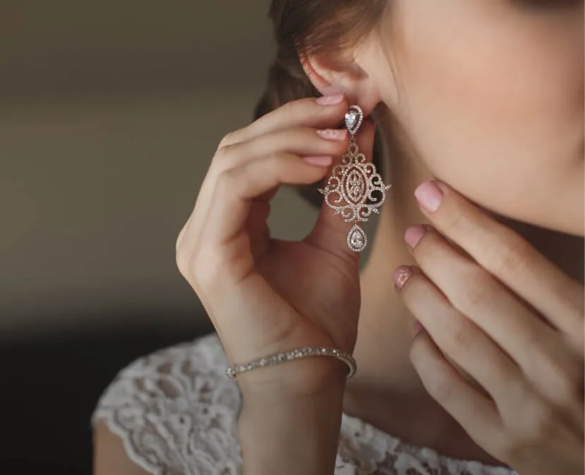 A bride fastening a diamond drop earring