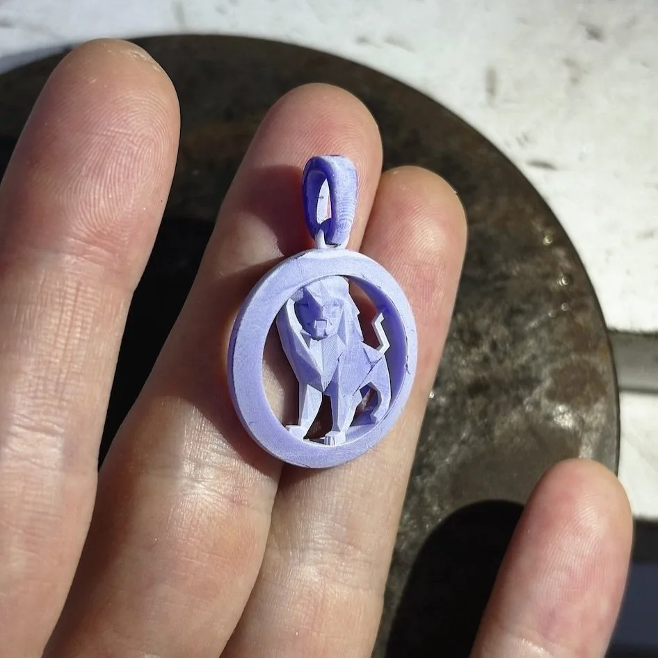 A wax model of the pendant held in hand.