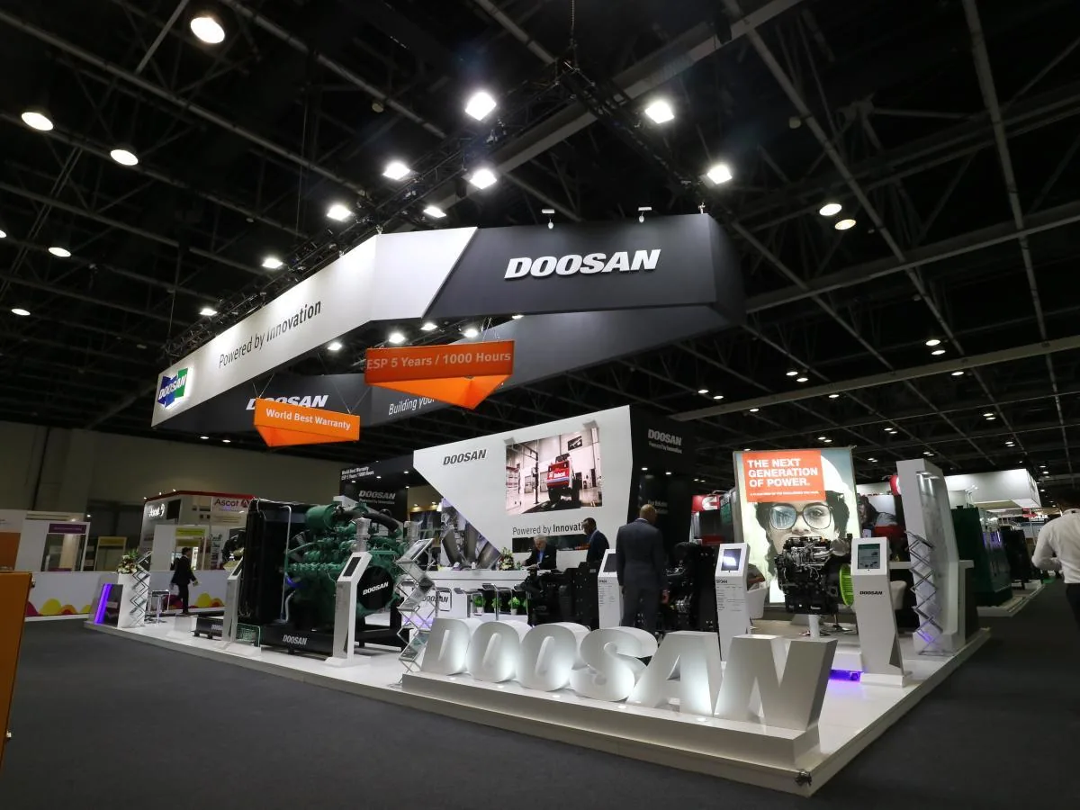 DOOSAN exhibition stand with overhead branding and lit product platforms