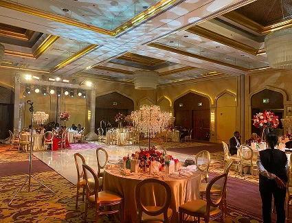 Grand ballroom wedding reception with floral centrepieces and stage lighting