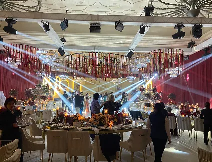 Wedding celebration with red drapery, hanging florals and dramatic beam lighting