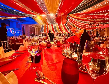 Wedding hall with richly draped fabric ceiling, fairy lights and warm table settings