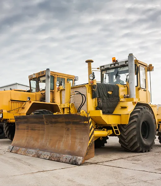 Heavy yellow earth-moving machinery on a hardstanding yard