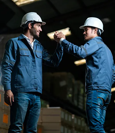 Two industrial workers acknowledging each other in a warehouse