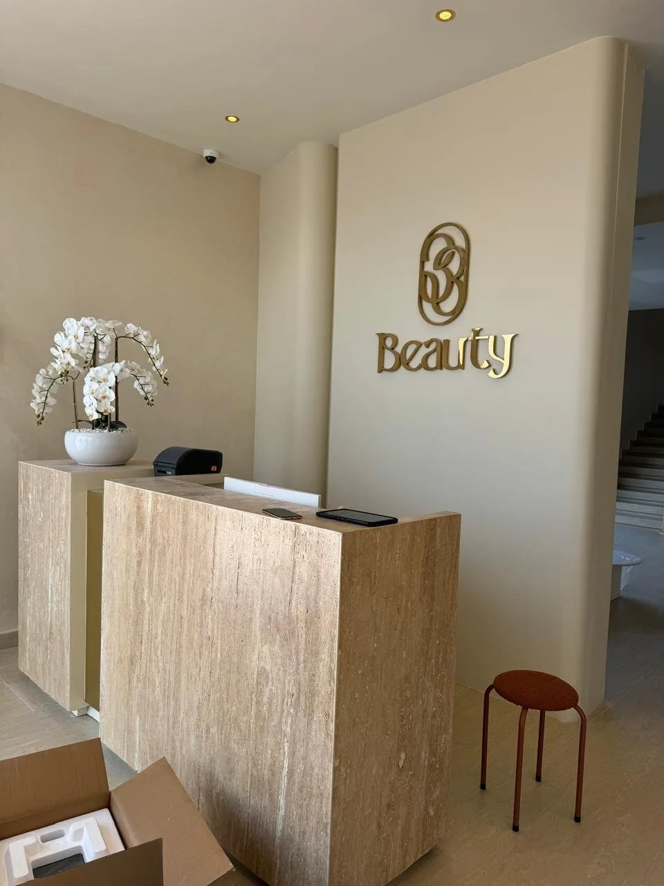 Beauty salon reception with travertine desk and brass signage