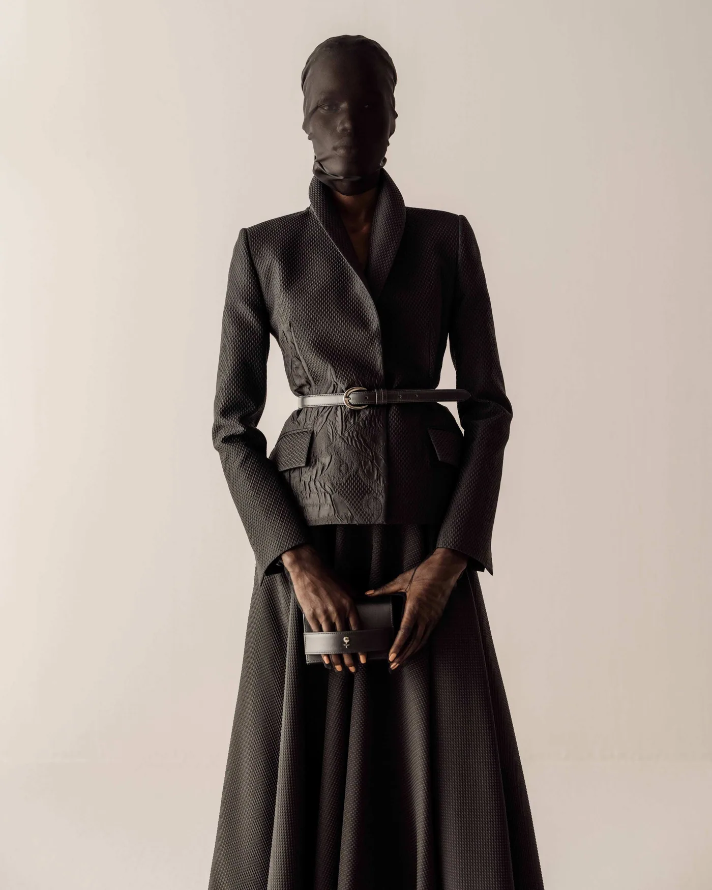 Silhouette in black jacquard, belted, with clutch