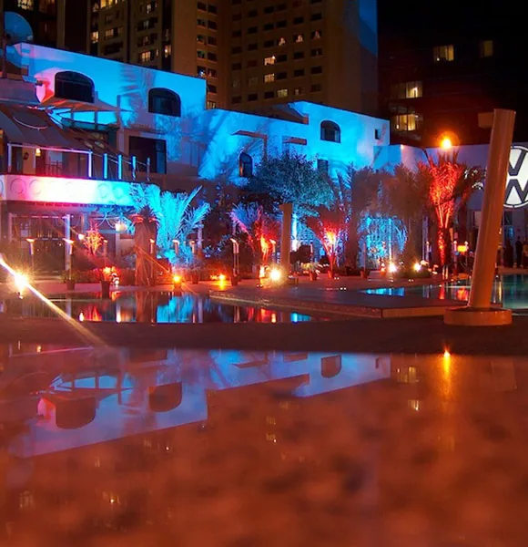 Poolside outdoor event lit in blue and amber at night
