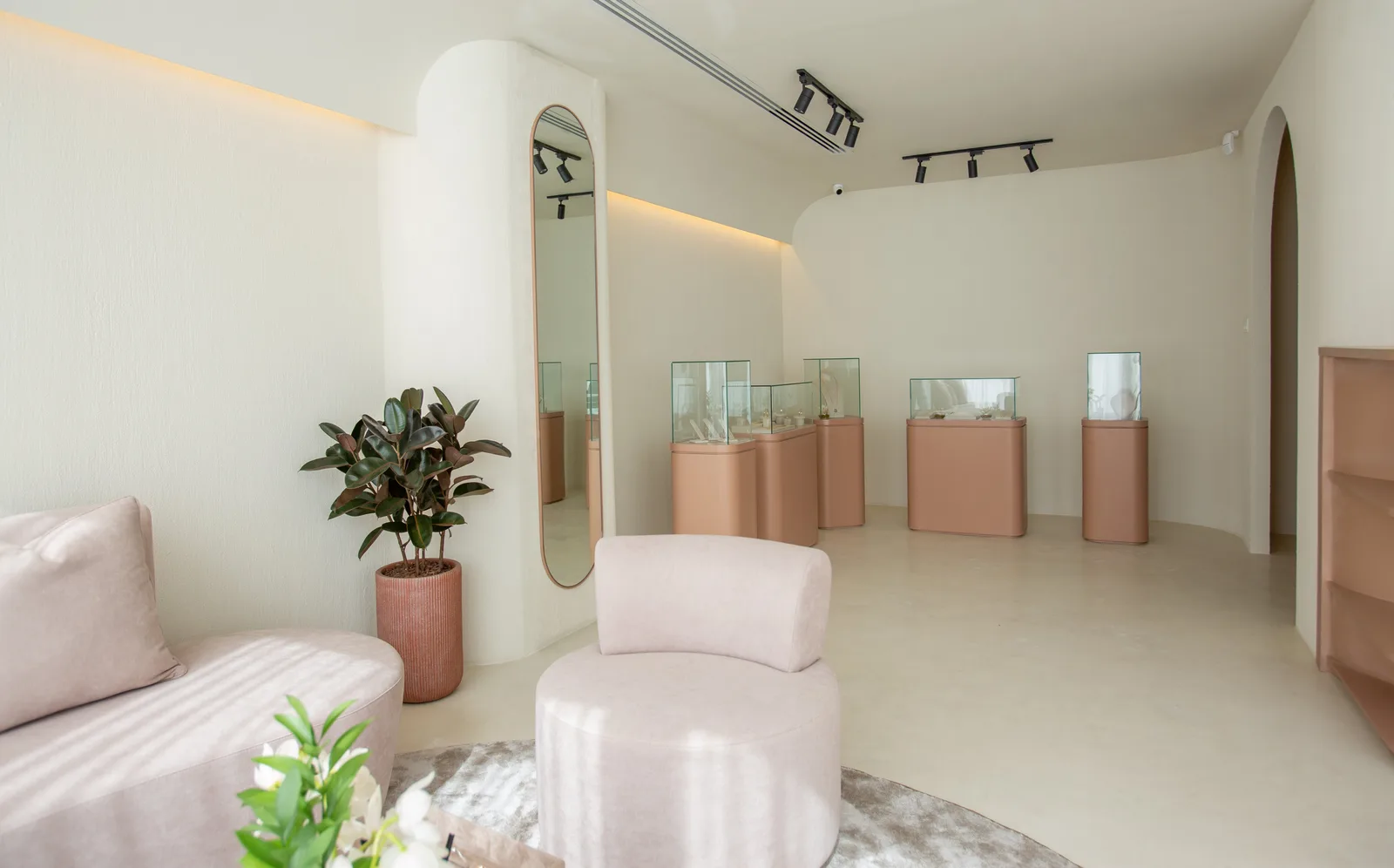 The ARQA private-viewing showroom in Dubai Design District — a soft, curved gallery space with rose-gold display pedestals