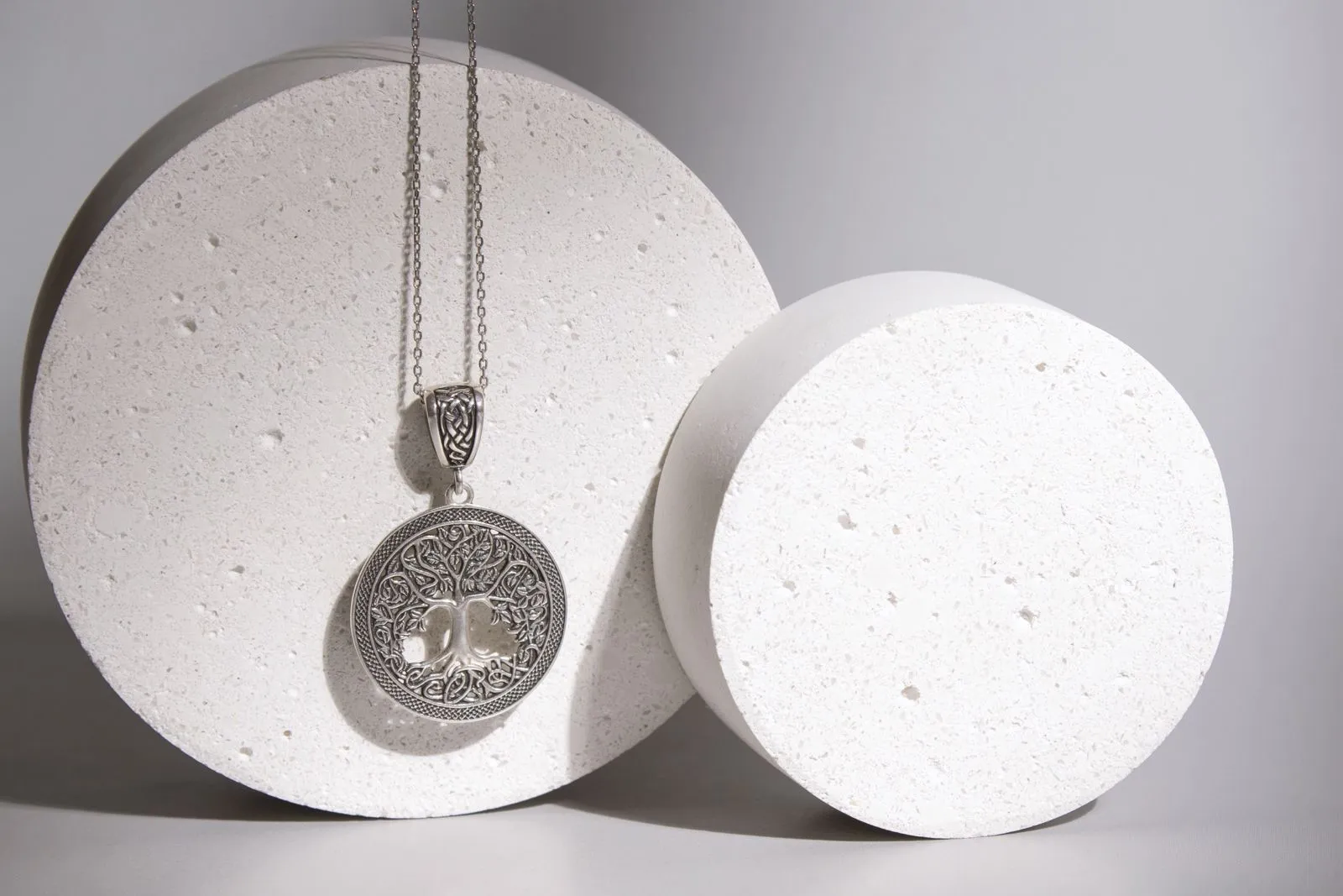 Sterling silver Tree of Life pendant resting against pale stone