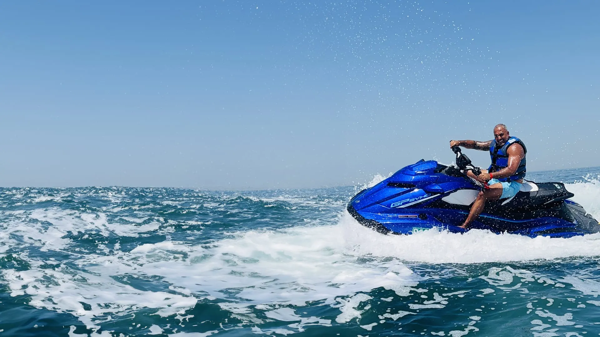 Rider on a jet ski cutting across the Gulf with Dubai on the horizon