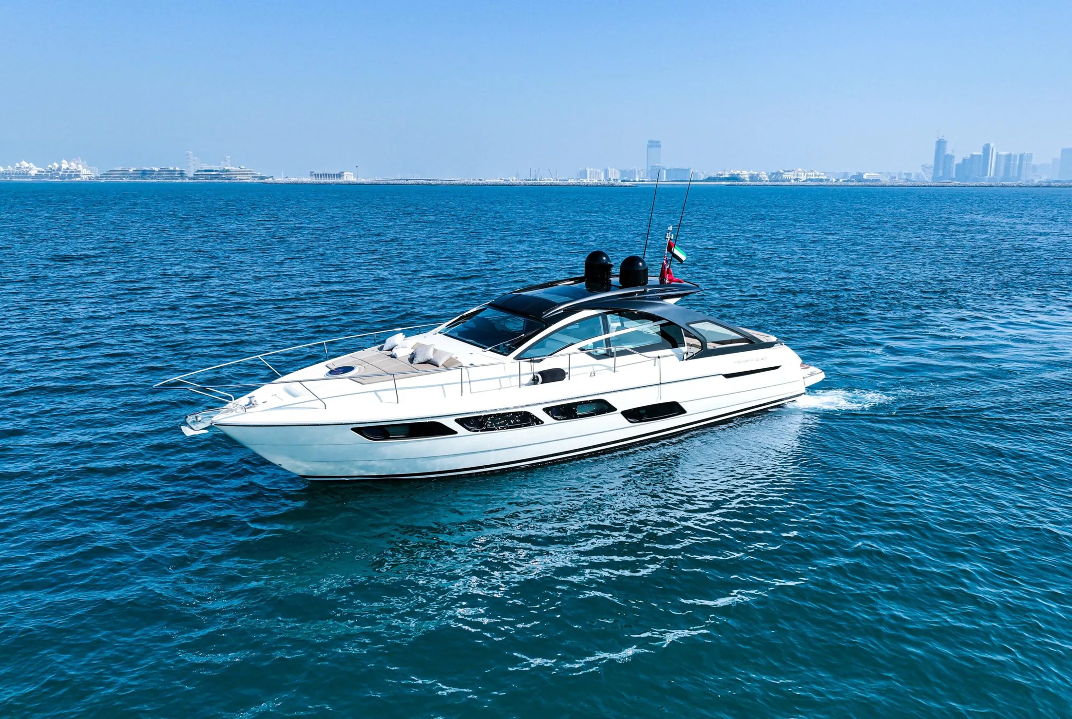 A luxury yacht cruising past Dubai's coastline at golden hour