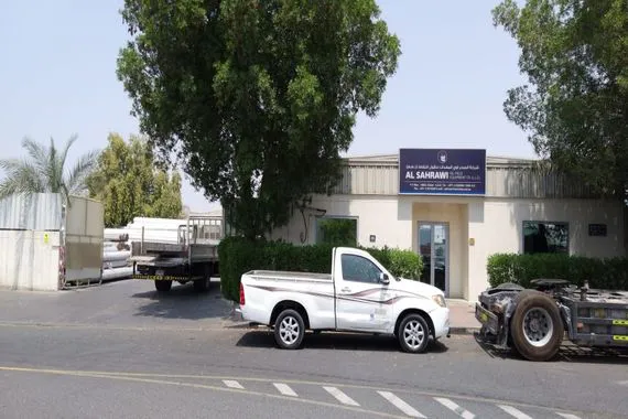 Al Sahrawi facility exterior with company vehicles and signboard
