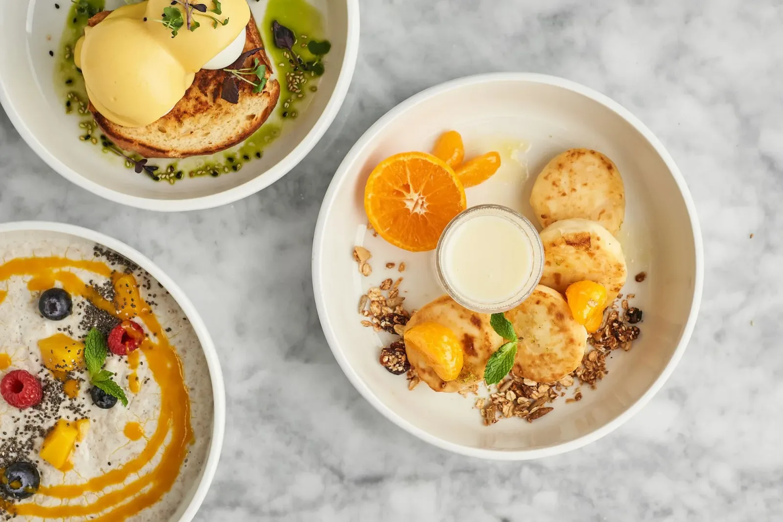 Breakfast plates with eggs benedict and granola bowl