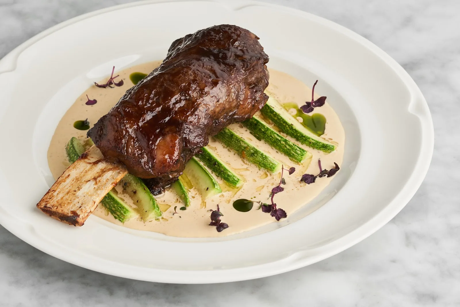A glazed slow-cooked lamb shank over courgette in a creamy sauce