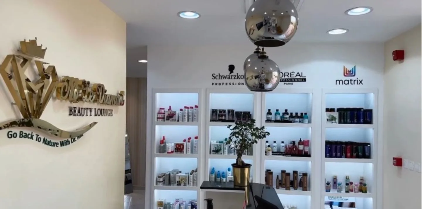 Reception wall with the gold M Le Diamant Beauty Lounge crest and shelves of professional hair products