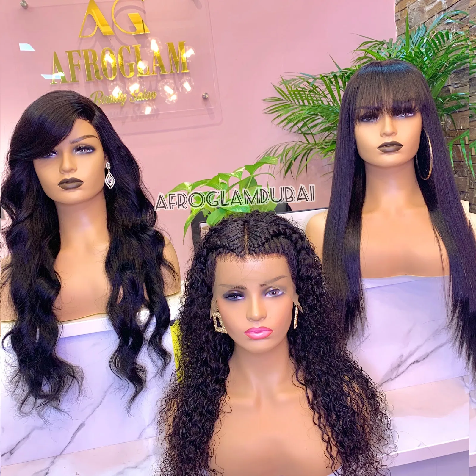 Display wigs on the gold-lettered pink wall