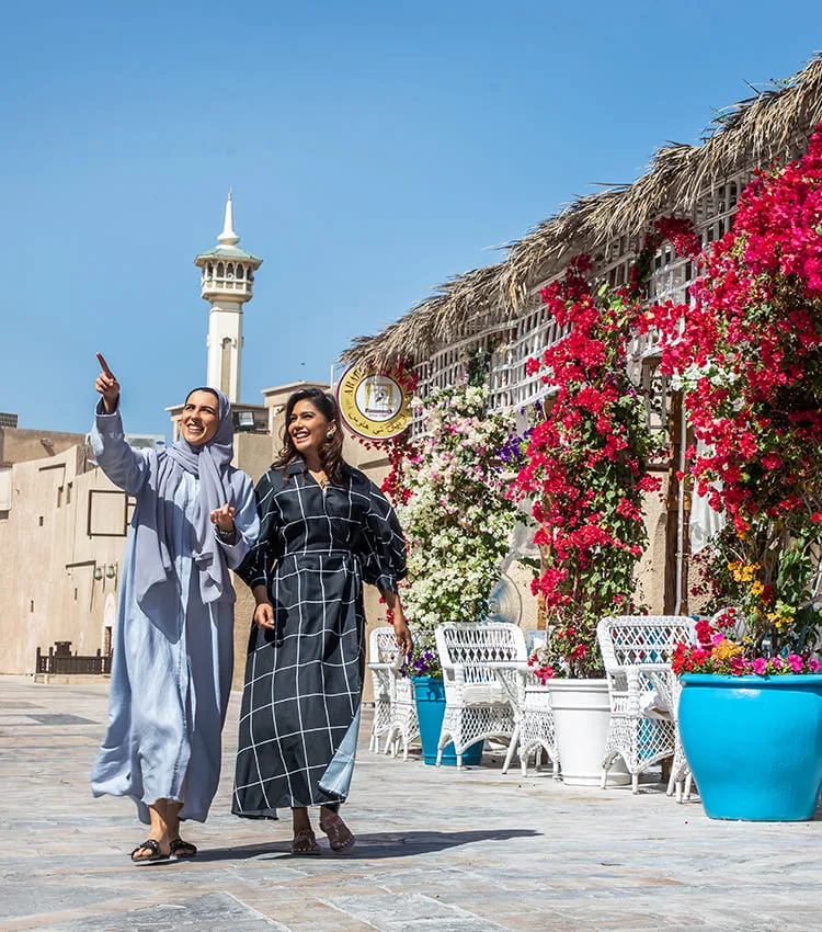 Two guests walking through the historic district past a flower-covered façade and a minaret