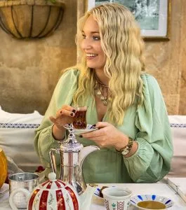 A guest enjoying tea with a traditional silver tea service in the foreground