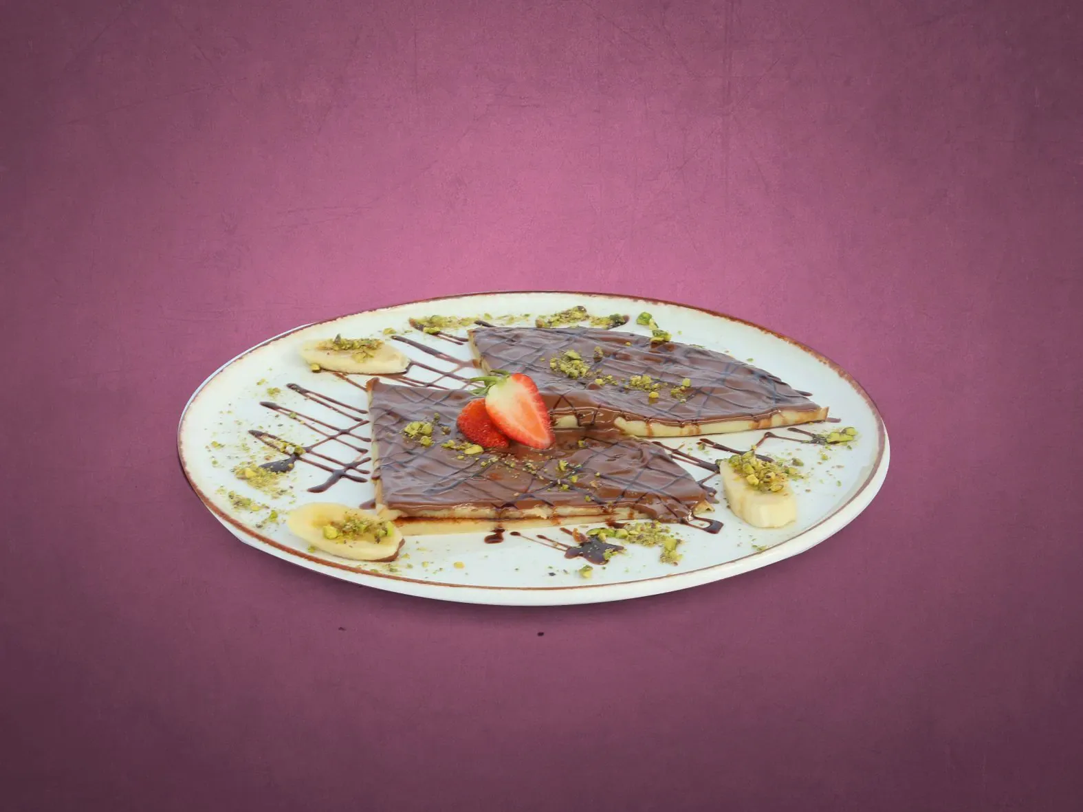 Chocolate crêpe dessert with banana, strawberry and pistachio
