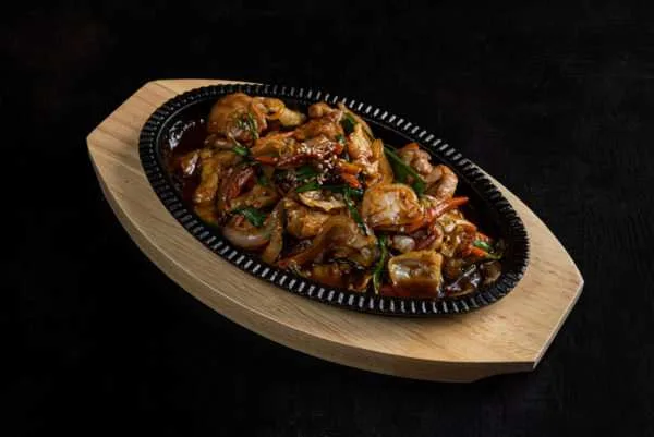Sizzling teppan dish with chicken and prawns on a wooden board
