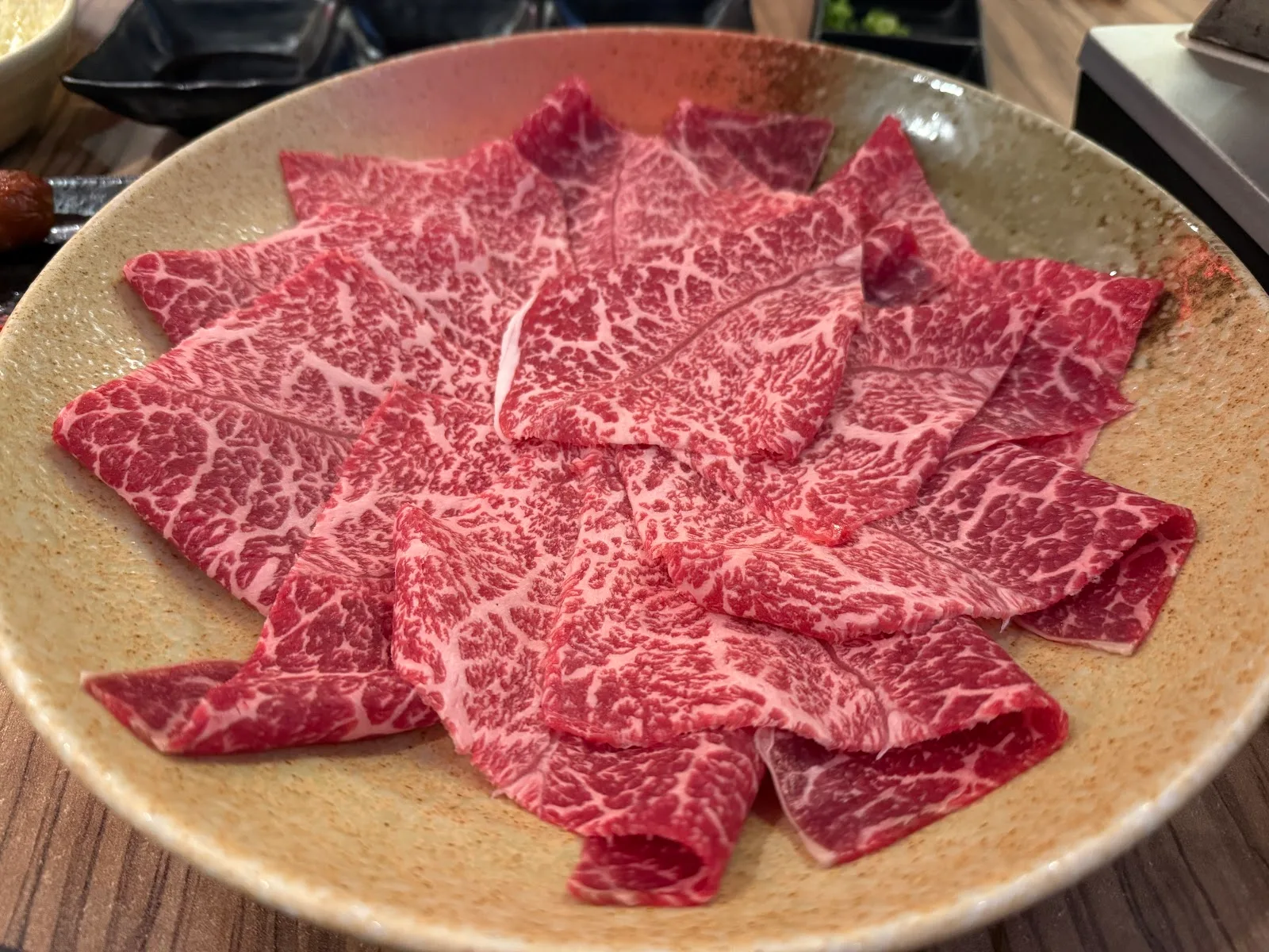 Marbled A4 wagyu slices fanned across a ceramic plate, ready for the grill