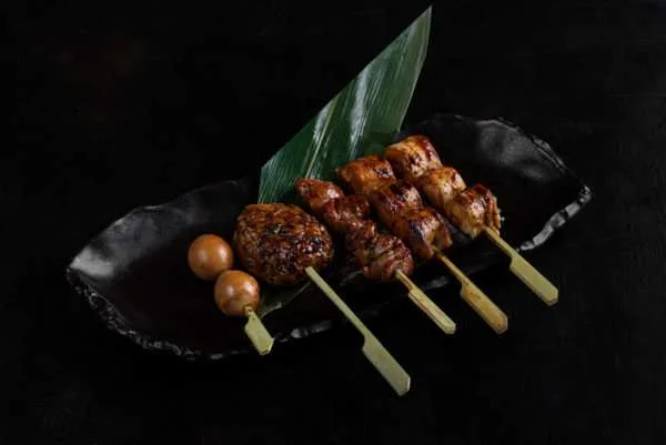 Grilled yakitori skewers on a black slate plate