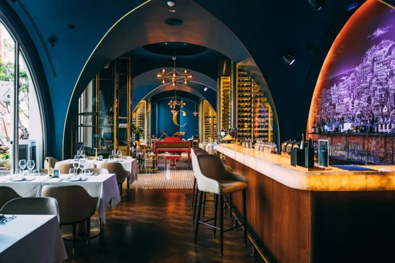 Praia's arched indoor bar with vaulted ceilings, a long marble bar and warm lighting