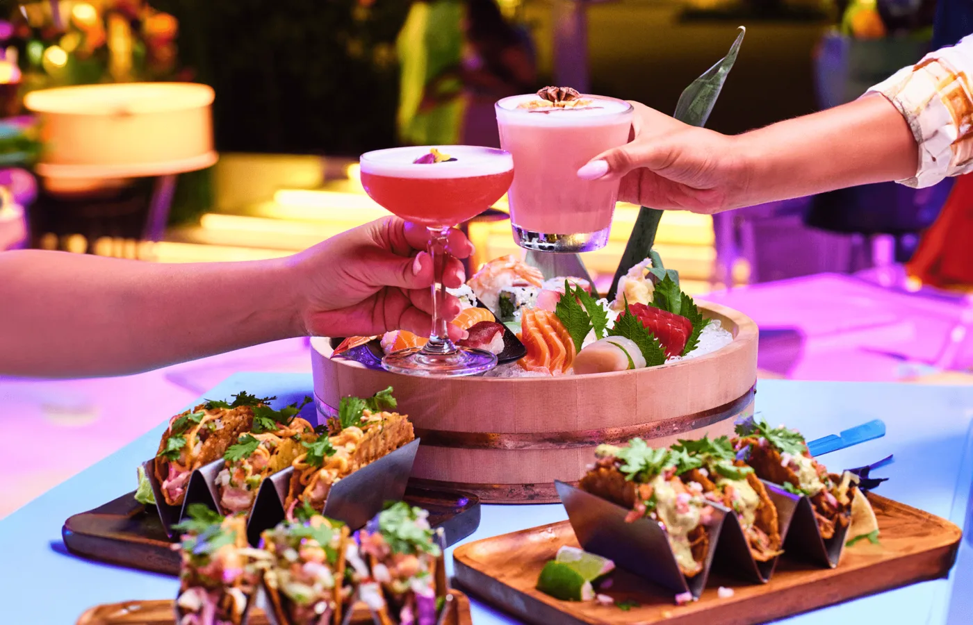 Tiered seafood and sashimi tower with oysters and grilled cuts on a terrace at night