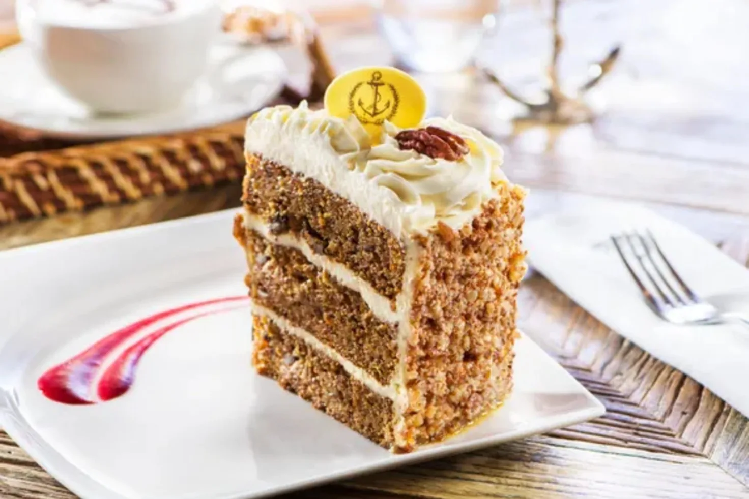 Slice of layered carrot cake topped with an anchor chocolate disc