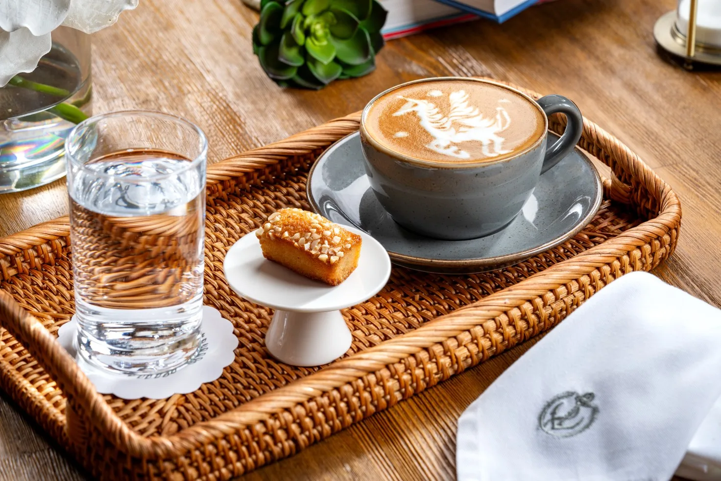 Latte with detailed latte art on a tray with a financier and water