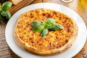 Margherita pizza with basil on a white plate
