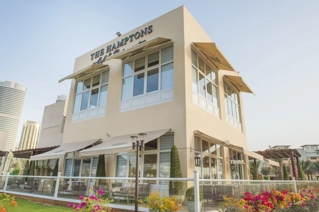 The Hamptons Cafe & Restaurant — two-storey coastal building with awnings and gardens on Jumeira Street, Dubai