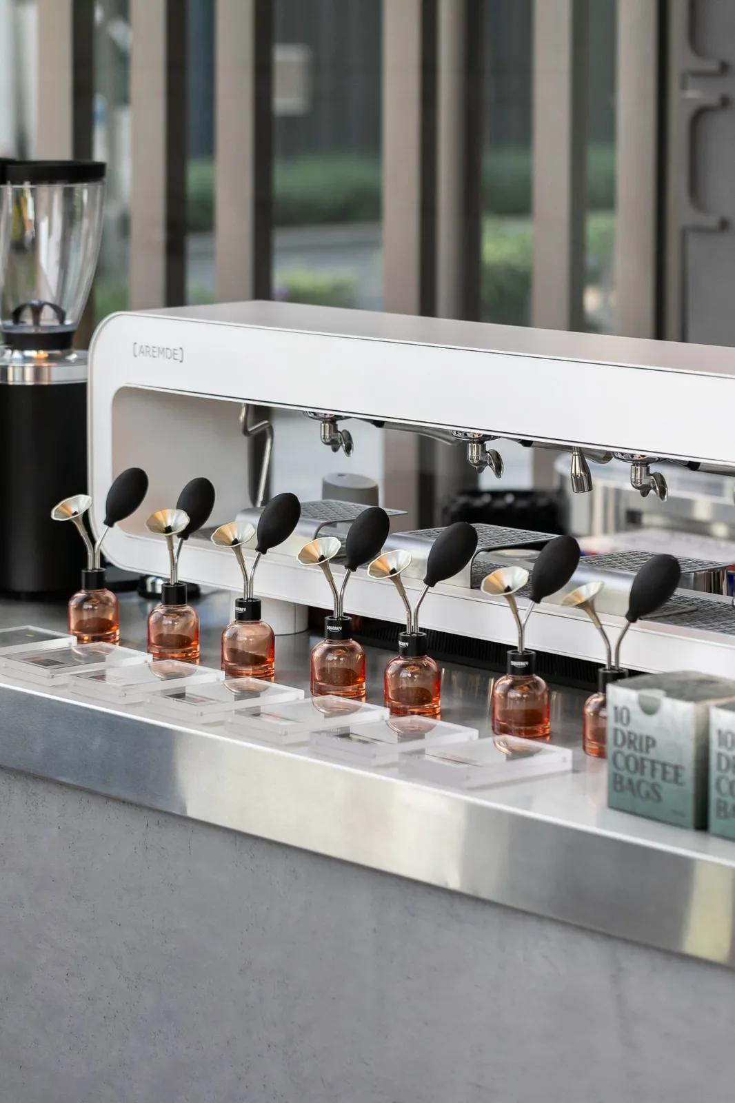 Multi-group espresso machine with row of dosing bottles on the Roasters coffee bar