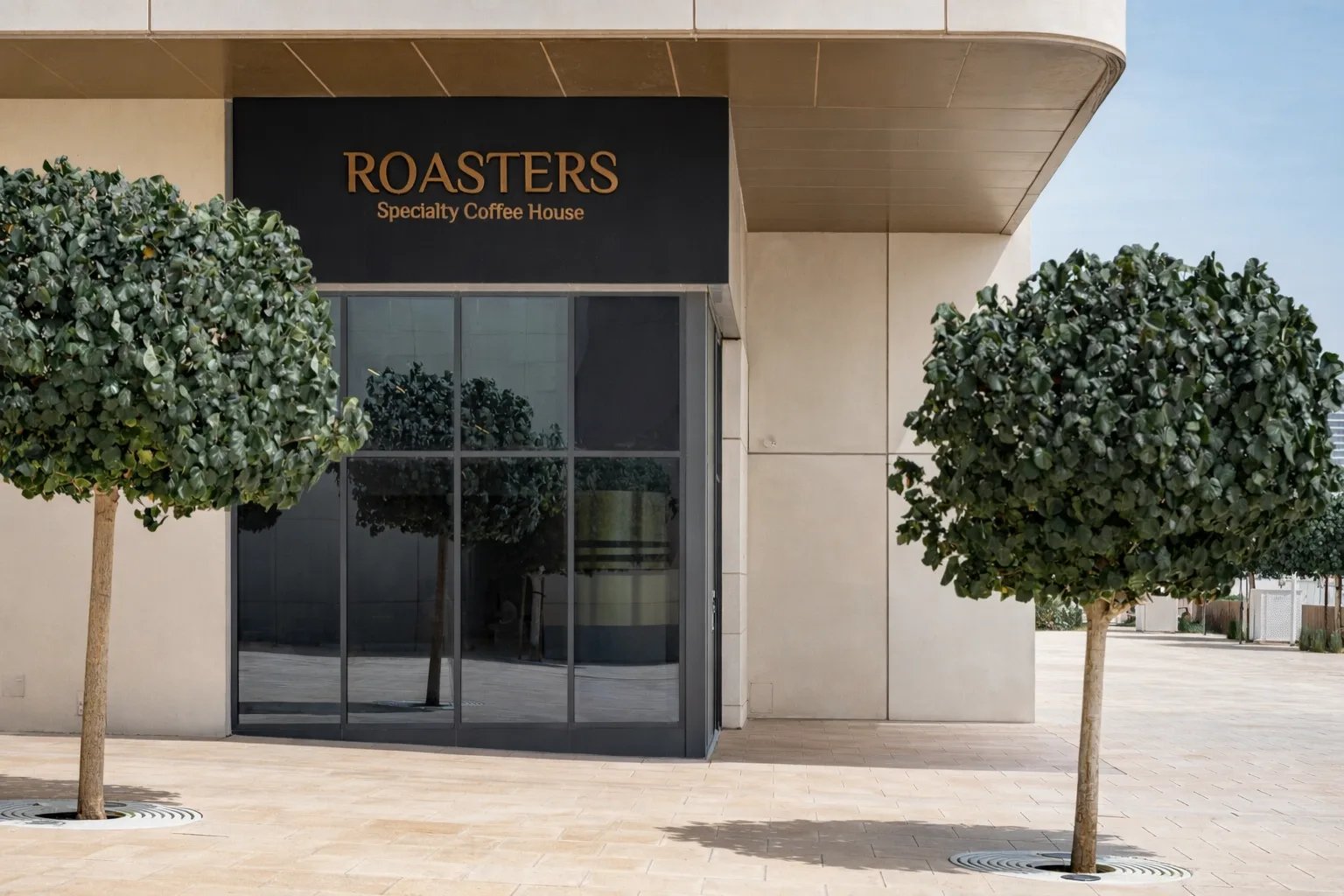Grey arched-window façade of Roasters Specialty Coffee House with outdoor café seating and a UAE flag
